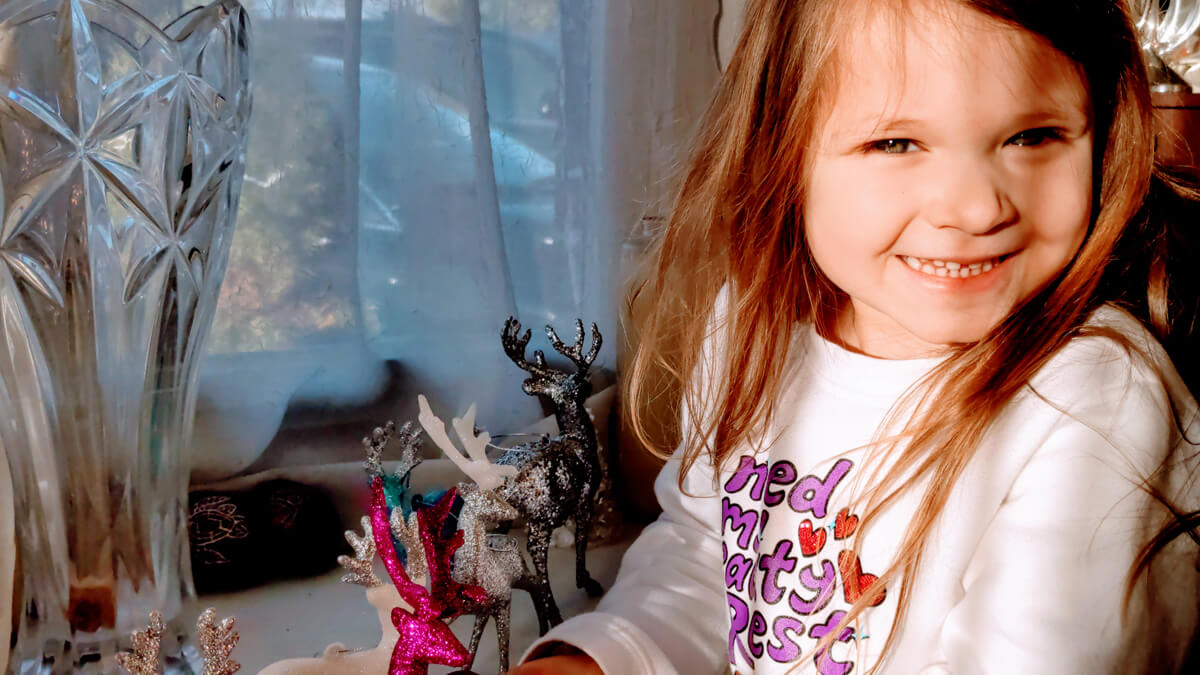 Little girl decorates the reindeer garden in the window as a nativity alternative idea