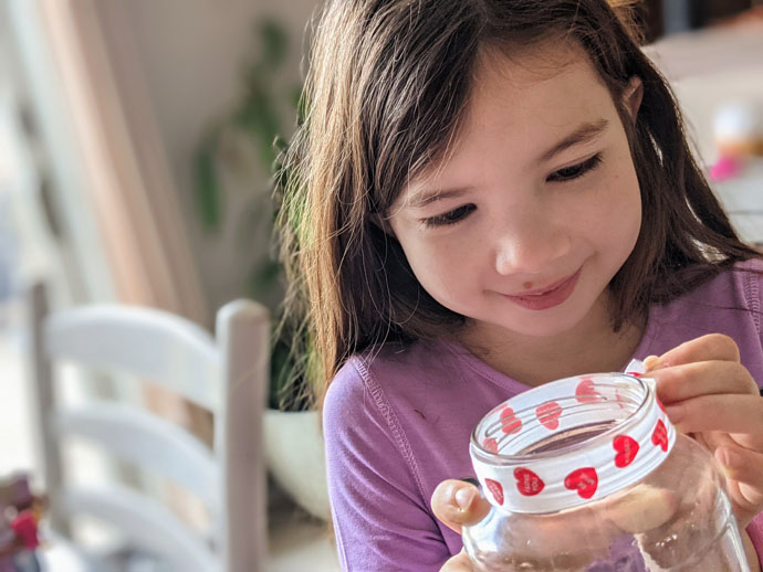 Reuse Old Candles for Kids Crafts - Young 8yo Girl Putting Heart Ribbon on an Empty Glass Jar