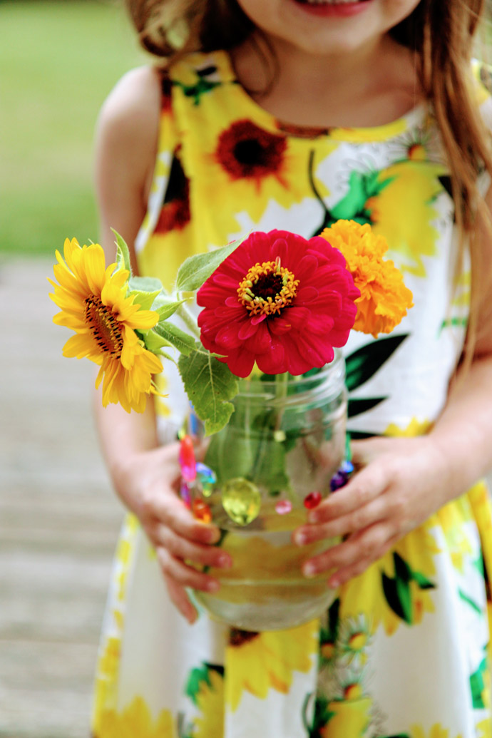 Little Daughter Holding Vase of Fresh Cut Flowers including Dwarf Sunflower Sunspot