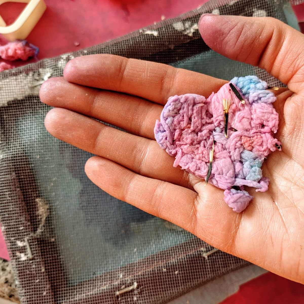 DIY Plantable Seed Paper Hearts in Pink, Purple, and Blue over a screen