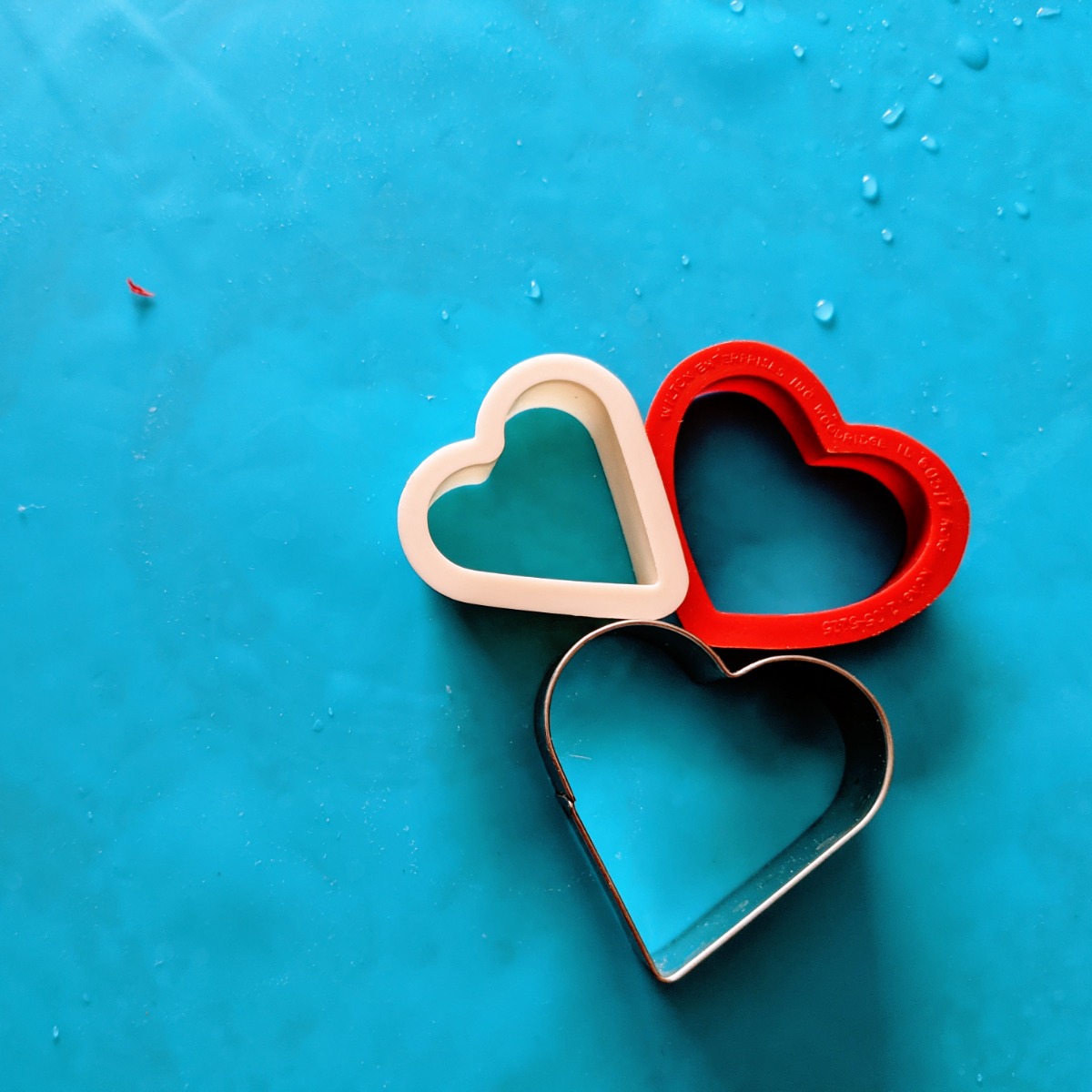 Trio of Heart Shaped Cookie Cutters on a Blue Background