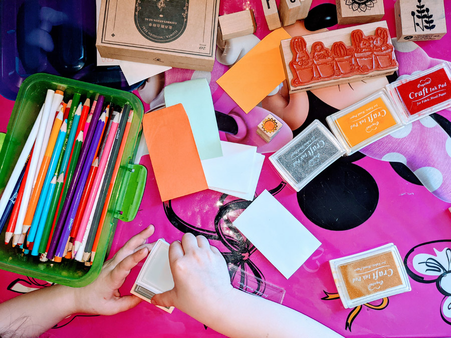 Garden Crafting Tools - Little Girl's Hands holding Wooden Stamper with bright colored ink pads and colored pencils