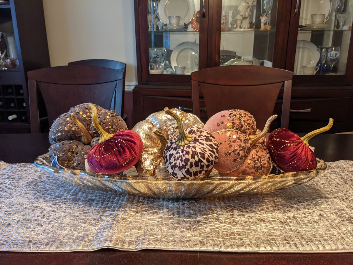 Plush decorative pumpkins in a long glass bowl in dining room