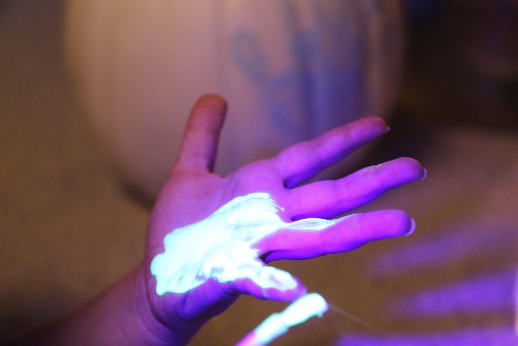 Daughter painting her hand with glow in the dark paint for a craft. 