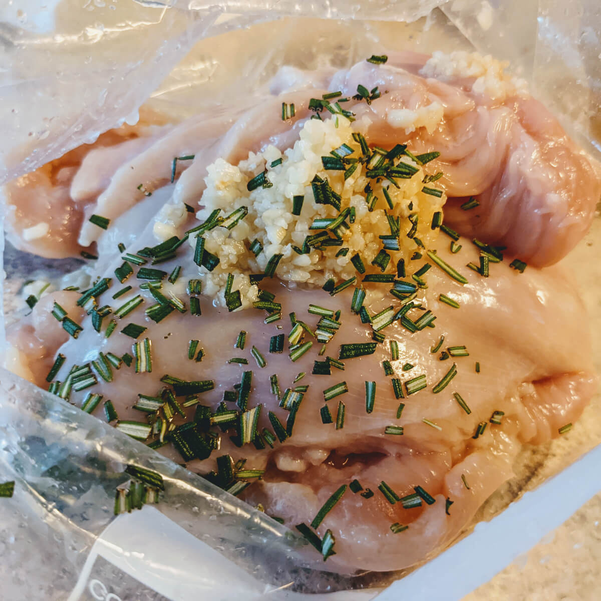 Poultry Seasoning Substitute Ideas - Rosemary and Garlic on Raw Chicken in a Plastic Baggie