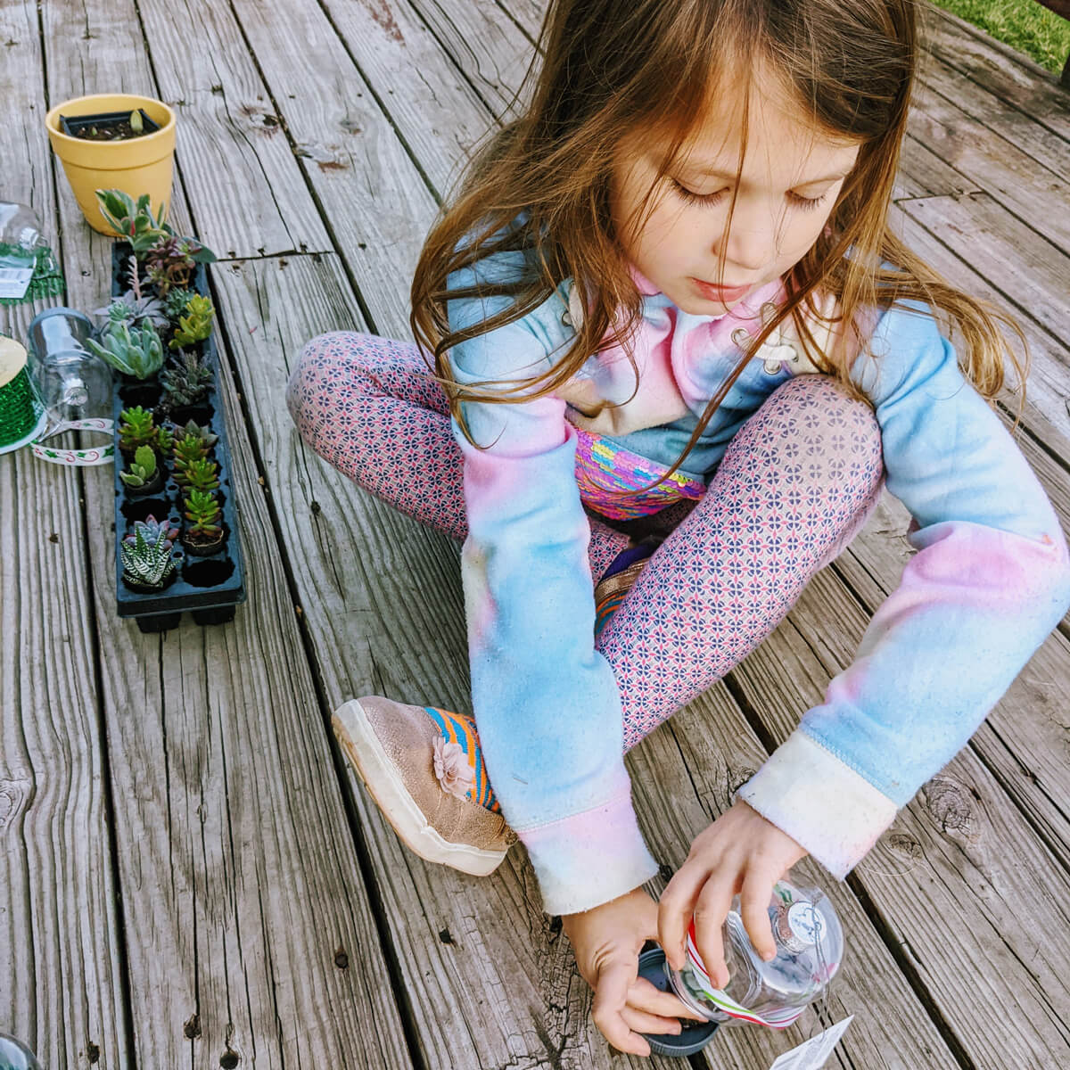 Little Girl Trying to Replace the Lid on the Terrarium Ornament