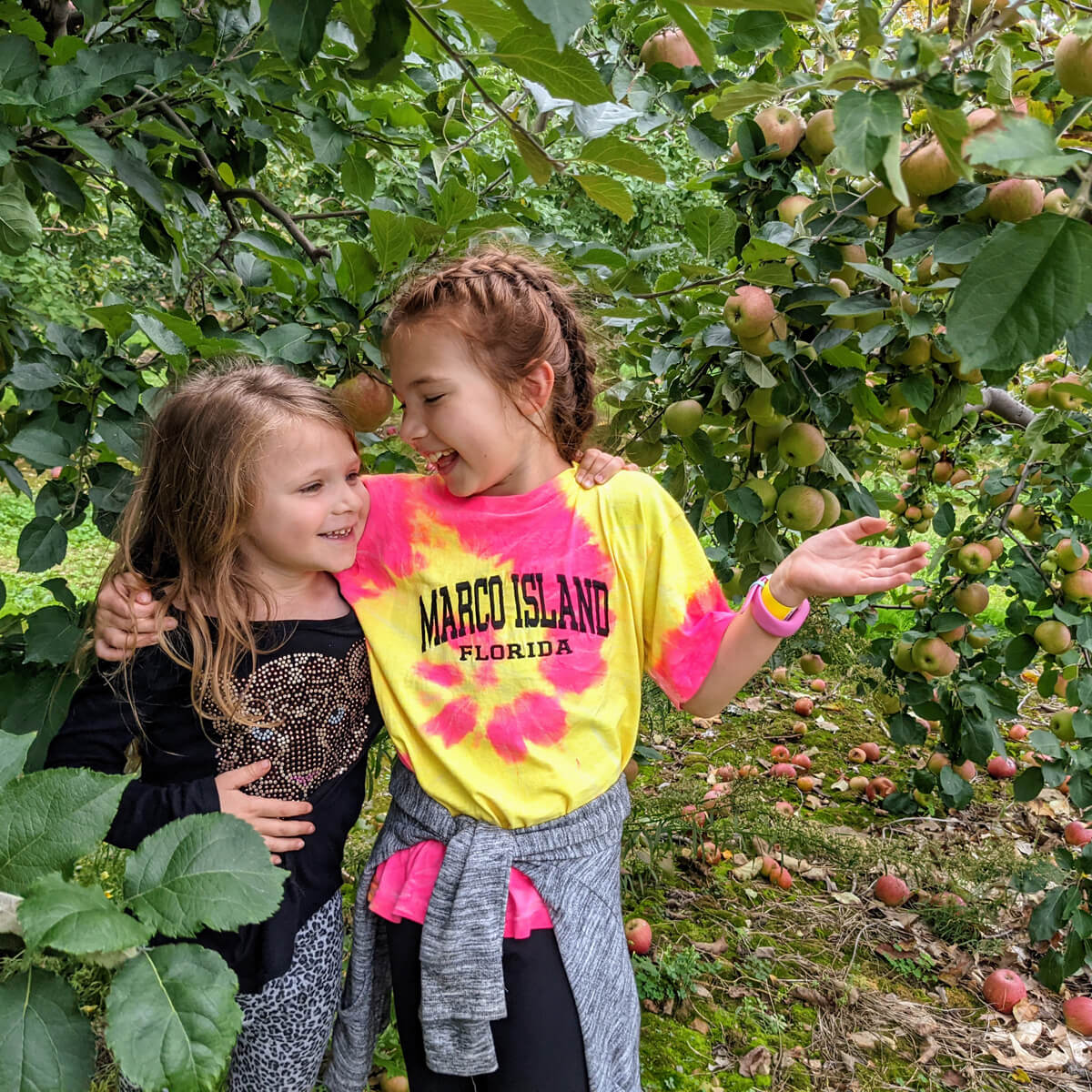 Young girls laughing in an apple orchard