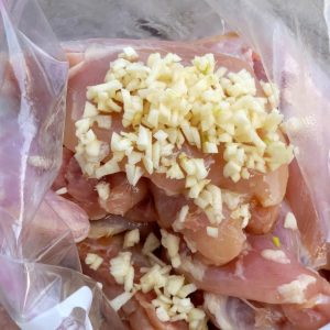 Raw Chicken Thighs Marinating with Diced Minced Garlic