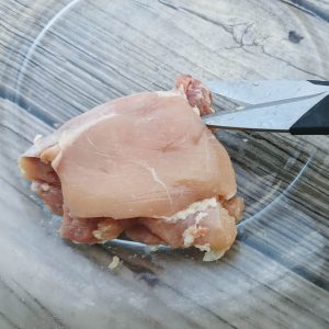 Trim fat from chicken thighs