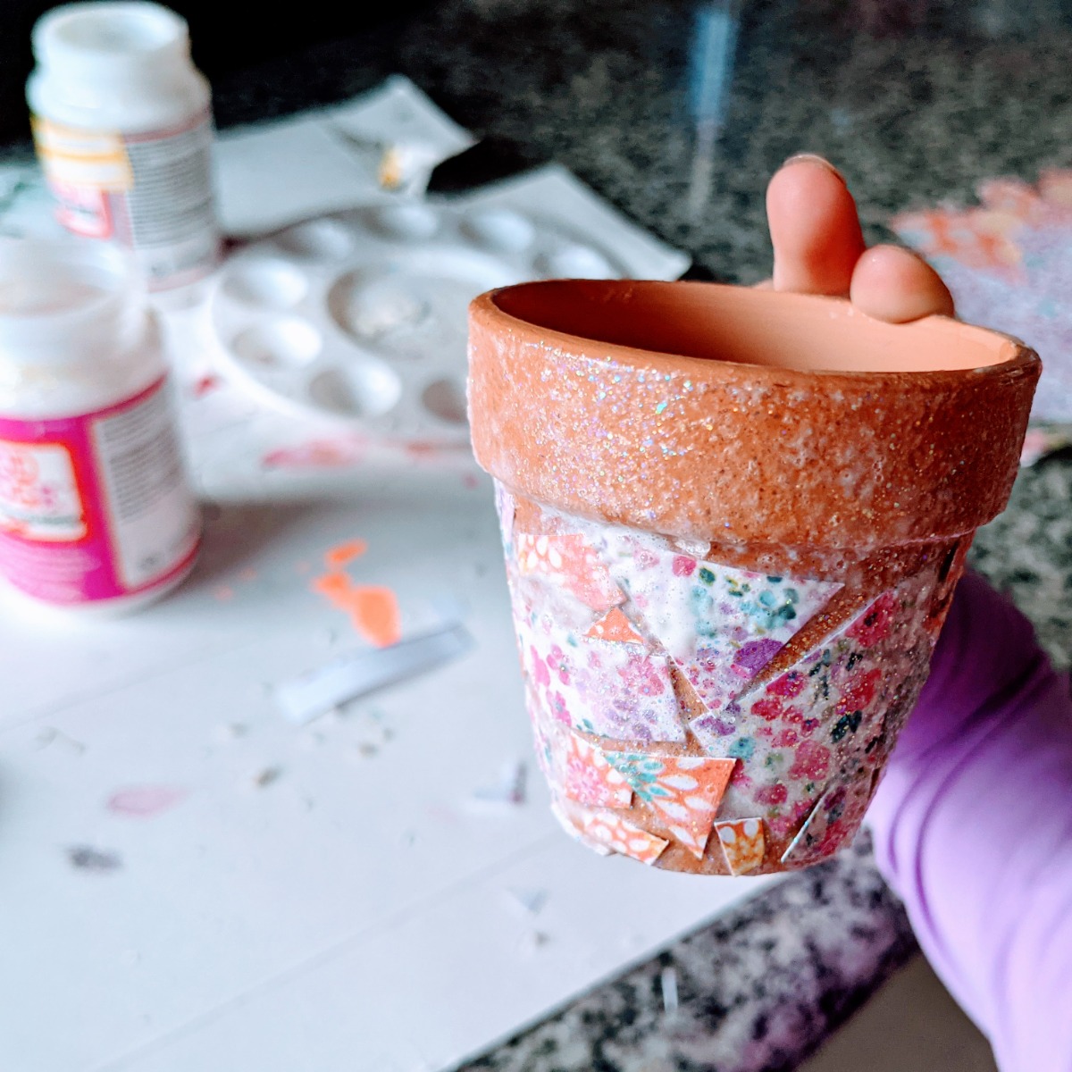 Little hand holding up a beautiful handmade mosaic flowerpot