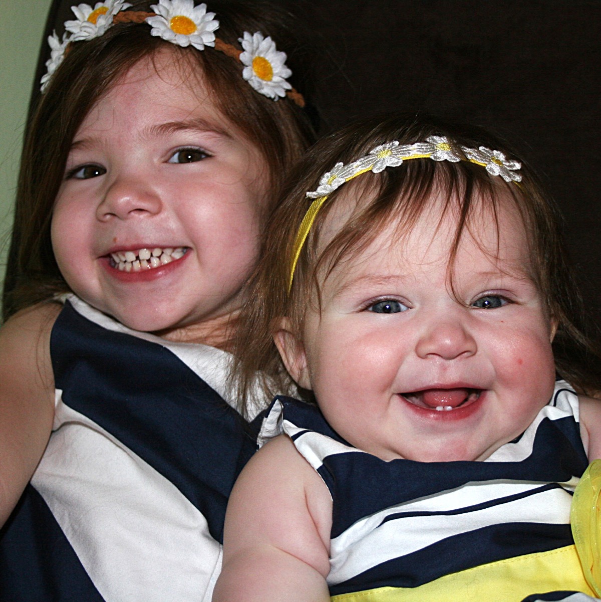 Sweet sisters wearing daisy headbands and navy blue and white striped dresses