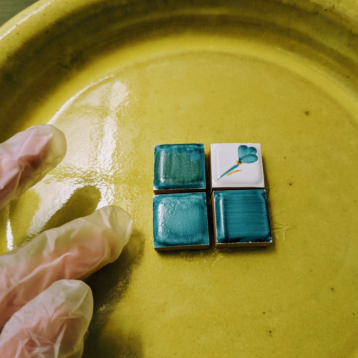 Center of pollinator watering dish with blue tiles on a chartreuse saucer