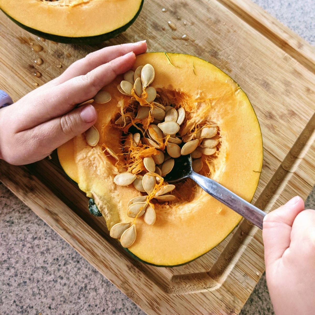 Saving Acorn Squash seeds for planting - daughter scooping seeds out of winter squash