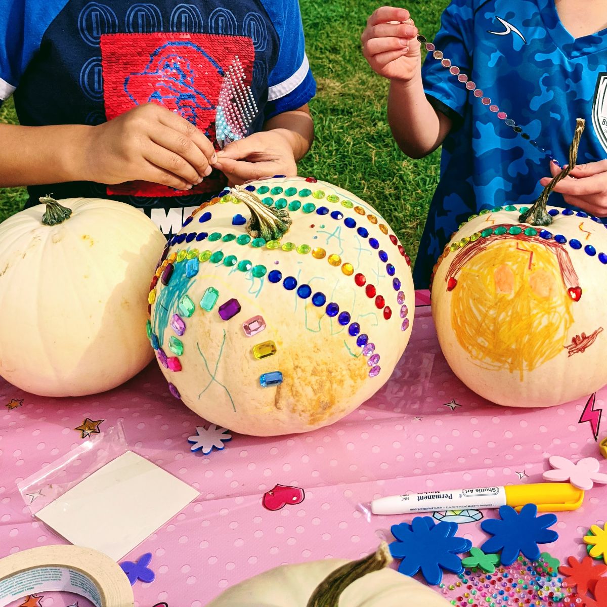 Boys adding gems to white pumpkins