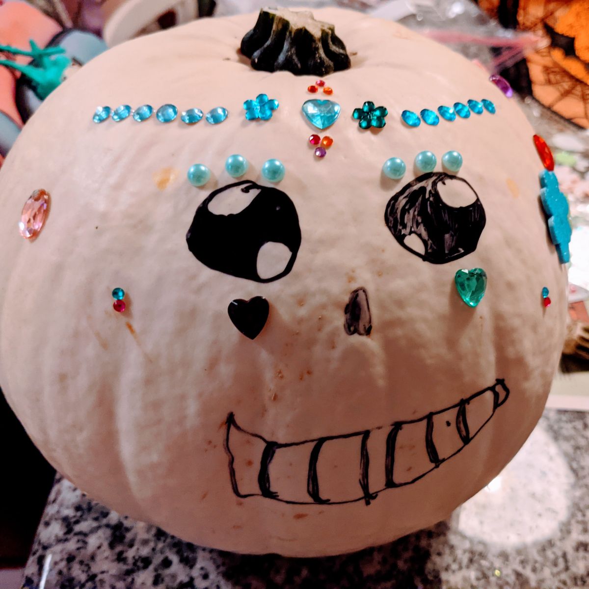 Smiling hand-drawn sugar skull pumpkin with rhinestone gems