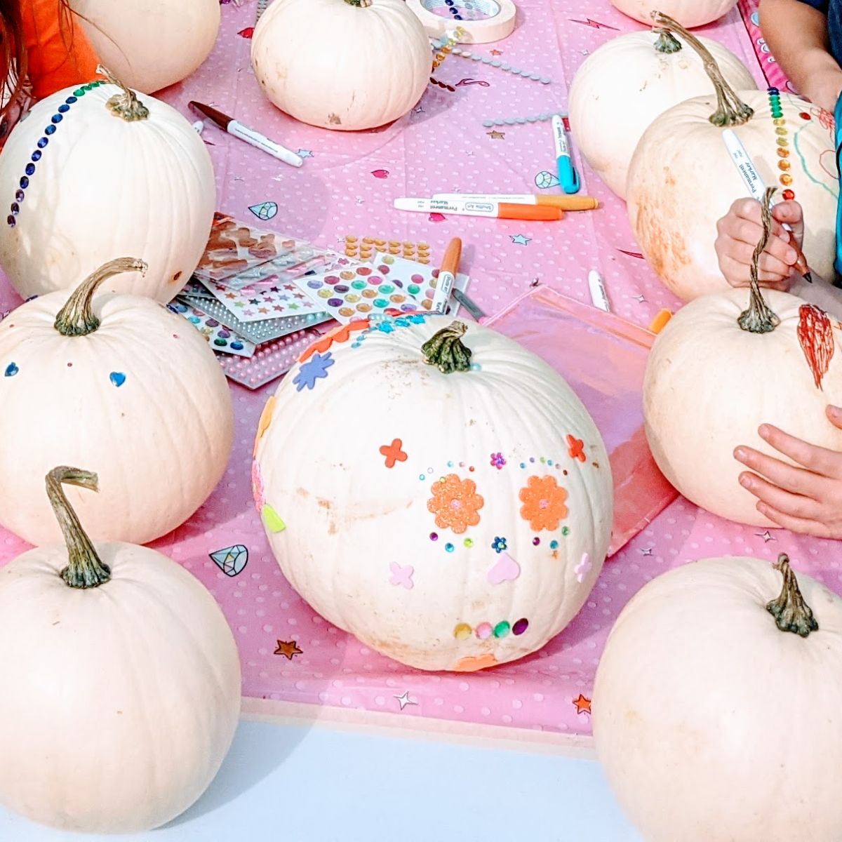 White pumpkins decorated like Mexican sugar skulls and arts and craft supplies