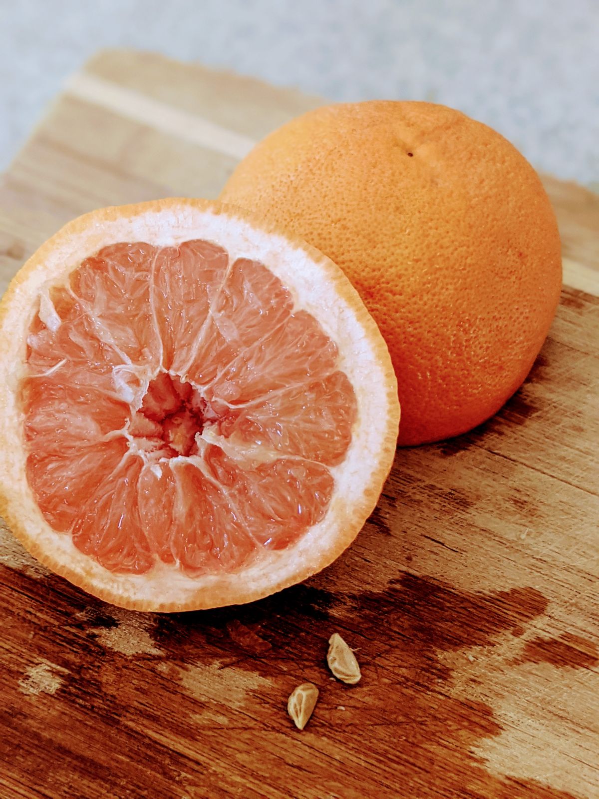 Sliced grapefruit on a cutting board with seeds