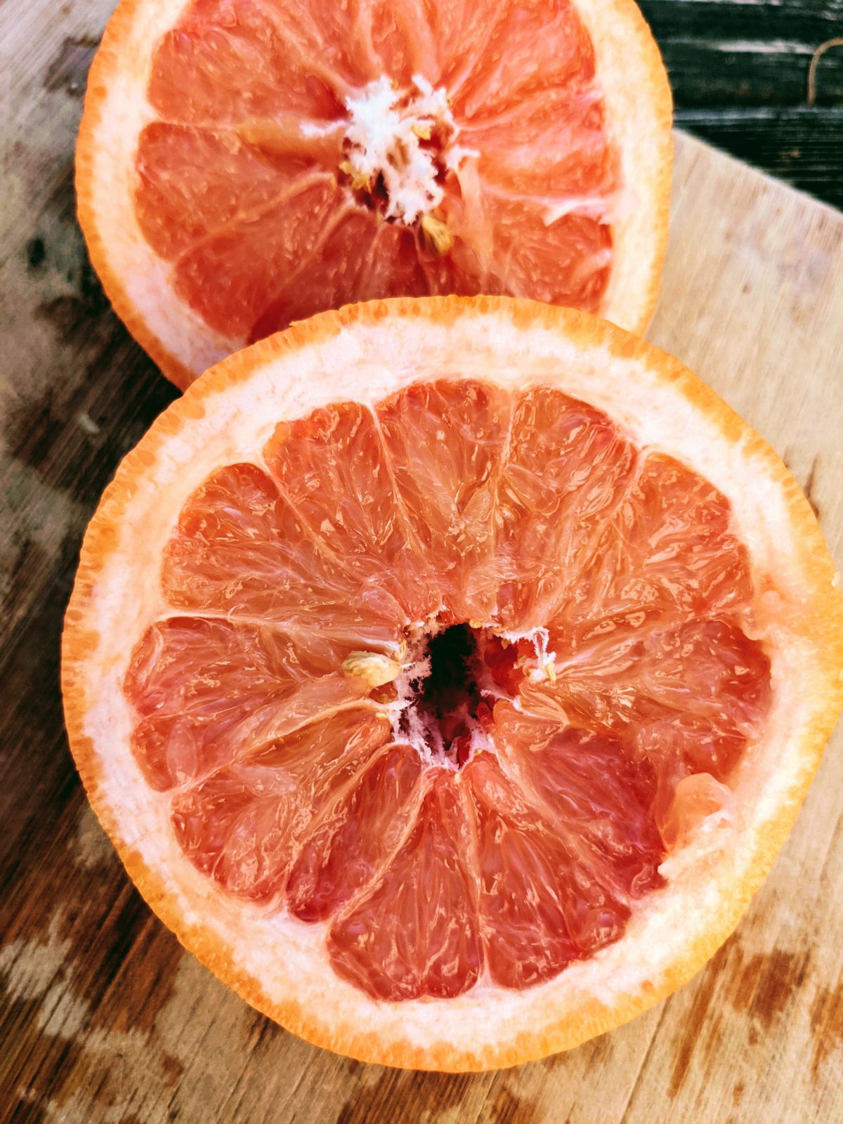 Sliced grapefruit cut in half on cutting board