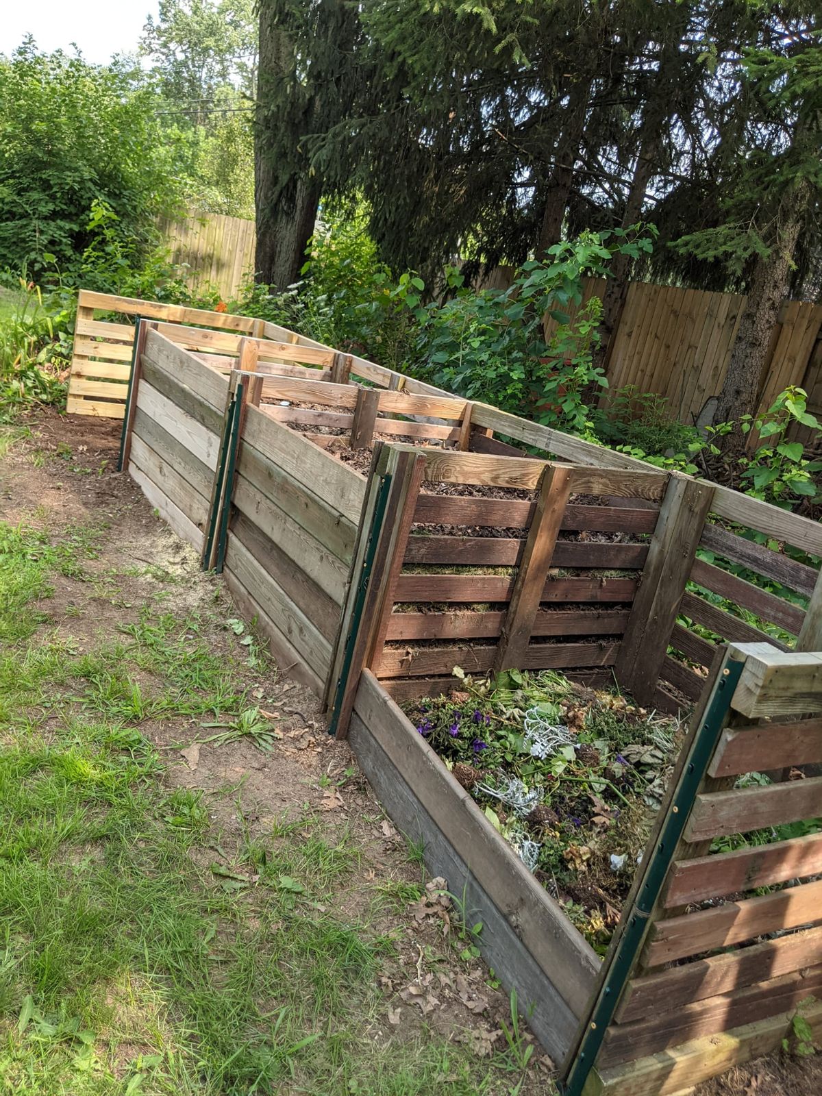 Four wooden compost bins, two ready to use and two hot bins; Photo courtesy of Cheryl Spieldenner 
