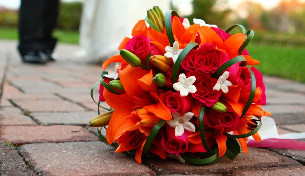 Hot pink roses, orange lilies, white stephanotis, and monkey grass in a wedding bouquet