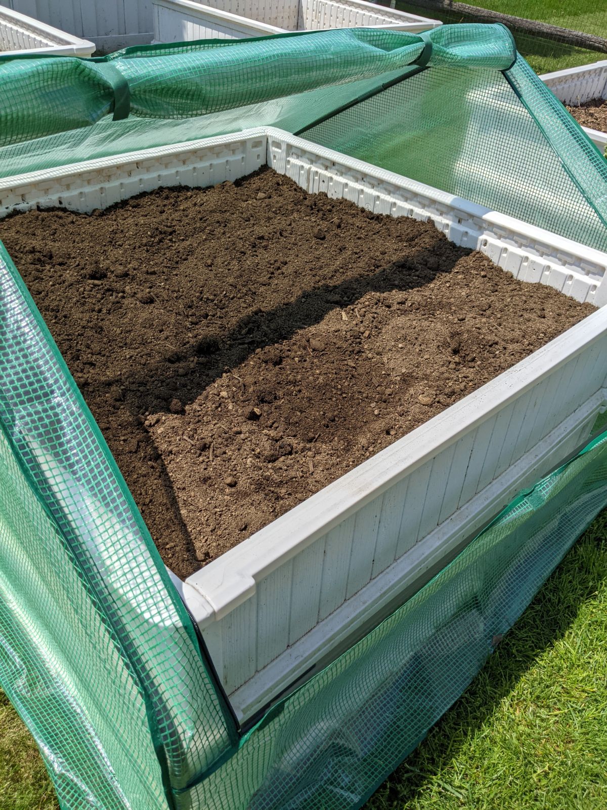 Open raised bed cover with empty soil ready for planting