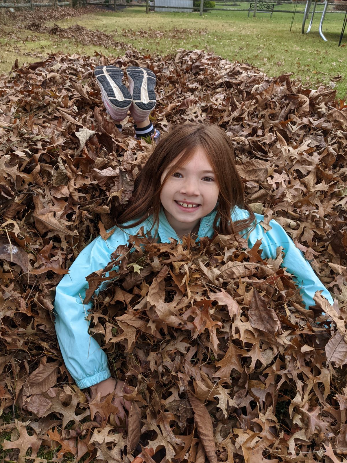 Daughter jumping in big leaf pile in fall