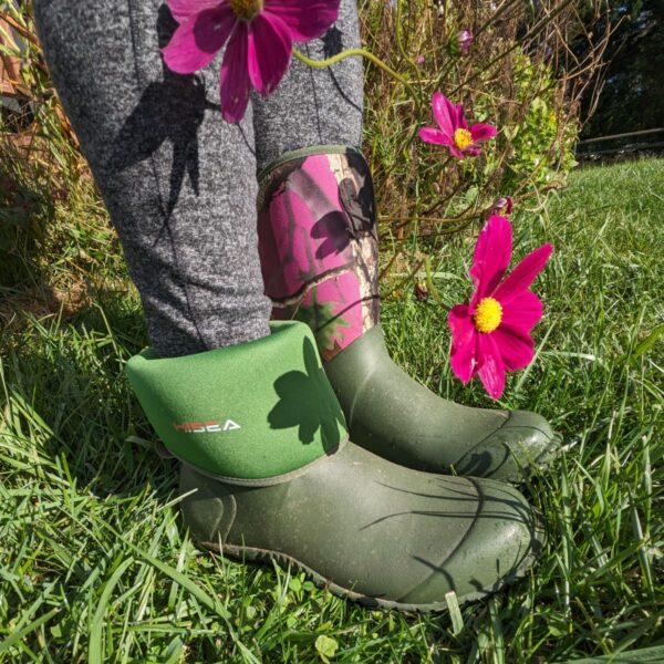 HISEA Garden Boots with on cuff folded down standing near some Cosmos