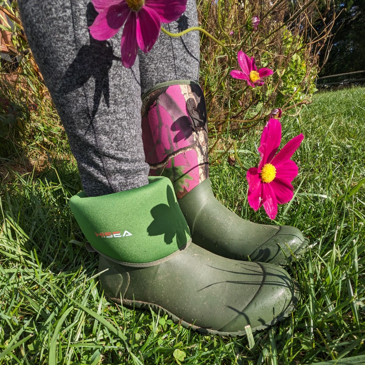 HISEA Garden Boots with on cuff folded down standing near some Cosmos